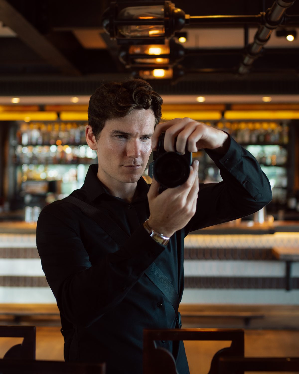 Luke Stimson, founder of Fogline Post, framing a shot with a camera in a warmly lit restaurant