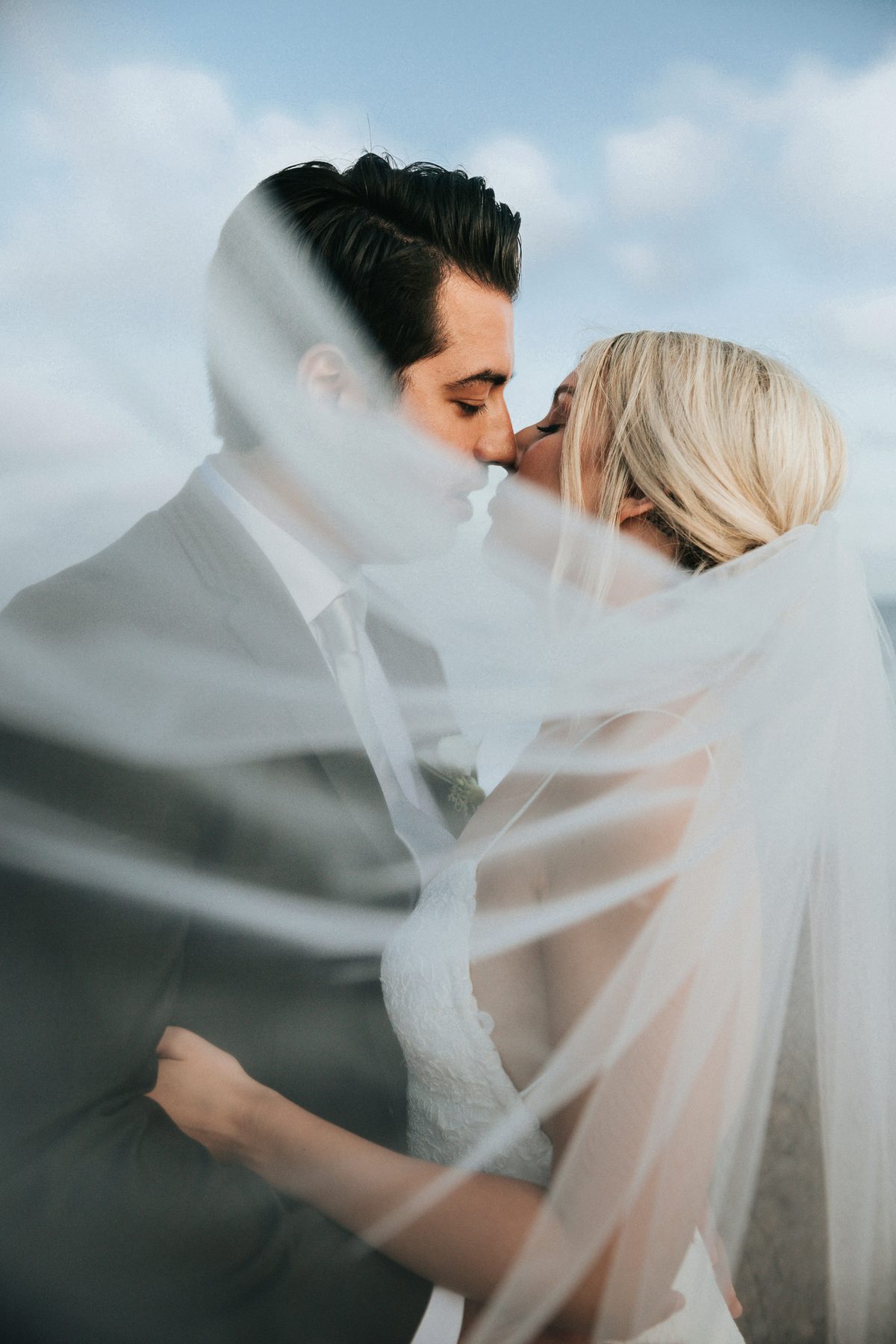 Unedited RAW wedding photo of a couple kissing beneath the veil